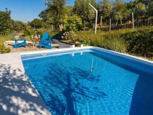 a blue swimming pool in a yard with two blue chairs at Marvão Country Houses - Queixos II in Santo António das Areias
