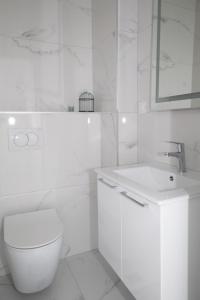 a white bathroom with a toilet and a sink at Celuga sea view apartments in Bar +8 photos