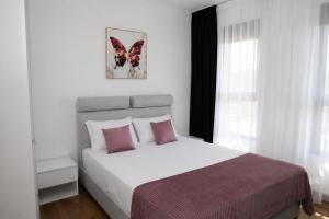 a bedroom with a large white bed with pink pillows at Celuga sea view apartments in Bar