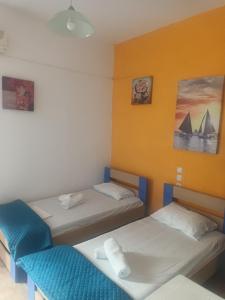 two beds in a room with yellow walls at nostalgo in Skiathos