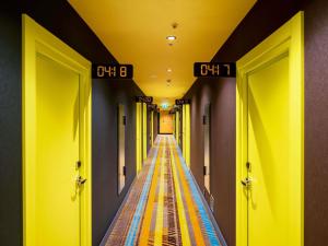 a hallway with yellow walls and a long aisle with clocks at ibis Styles Batumi Hotel in Batumi