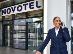 a woman in a suit talking on a cell phone at Novotel Abidjan Marcory in Abidjan