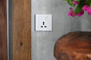 a white lightswitch on a gray wall with pink flowers at Dive and Sleep - All Inclusive Diving Guesthouse - 3 Dives per day in Maamigili