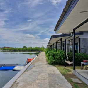 a building with a dock next to a river at มีดี ฟาร์ม โฮมสเตย์ in Ban Klam