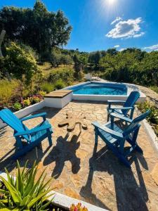 a patio with two blue chairs and a swimming pool at Marvão Country Houses - Queixos I in Santo António das Areias +11 photos