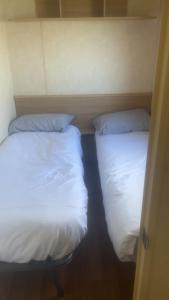 two beds in a room with white sheets and pillows at The Colorado van in Rhyl