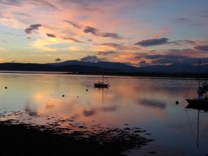 a boat sitting on the water at sunset at Ards House in Oban