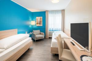 a hotel room with two beds and a desk at Hotel Westerfeld in Hemmingen