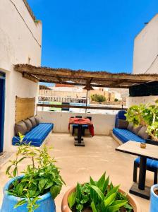 a patio with blue couches and tables and plants at Hôtel grand Atlas in Mirleft