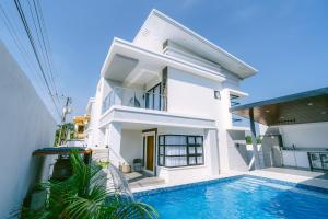 a white house with a swimming pool in front of it at Amethyst Bcd in Bacolod