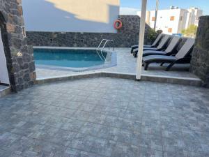 a swimming pool with lounge chairs next to a building at Kelenis Apartments in Karterados