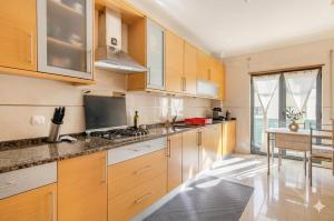 a kitchen with wooden cabinets and a stove top oven at To Be Apartments in Bobadela