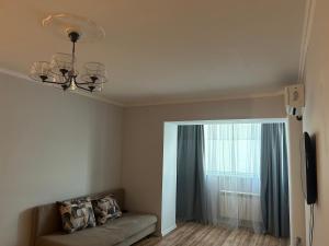 a living room with a couch and a window at Minimalist 2-room Apartment in Aktobe