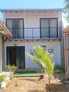 a house with a balcony and a palm tree at Casa Berenice in Zorritos