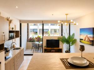 a kitchen and living room with a table and a tv at Syrena Luxury Caribbean - Heart of Playa del Carmen - Sea Views in Playa del Carmen