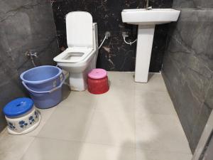 a bathroom with a toilet and a sink and buckets at Madan Usha Resort in Chitrakoot