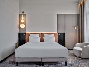 a bedroom with a large white bed and a chair at Mövenpick Grand Hotel Wroclaw in Wrocław +219 photos