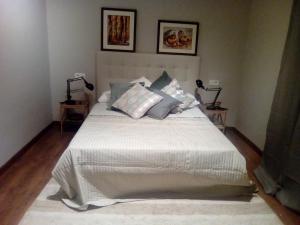 une chambre avec un lit avec des draps blancs et des oreillers dans l'établissement Jan&Joan Apartment, à Bilbao