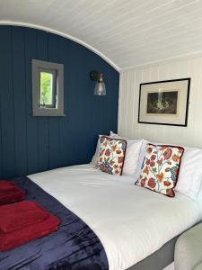 a bedroom with a large white bed with blue walls at Tower Farm Holidays - Glamping in Llangollen