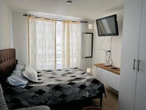 a bedroom with a bed and a flat screen tv at Apartamento floral in Tunja
