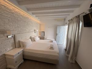 a bedroom with a white bed and a brick wall at Casa Bianca in Ornos +117 photos