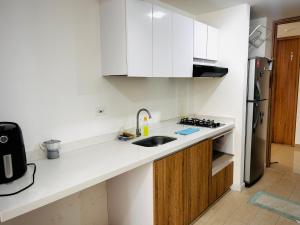 a white kitchen with a sink and a refrigerator at Apartamento floral in Tunja