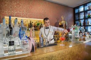 a man standing behind a bar making a drink at Hotel A La Commedia in Venice