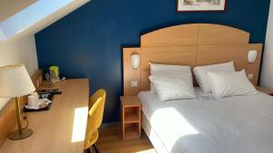 a bedroom with a bed and a desk with a lamp at Kyriad Cambrai in Cambrai