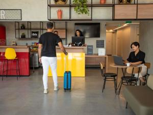 a man with a suitcase and a woman in an office at Ibis Serra Talhada in Serra Talhada