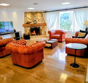 a living room with leather furniture and a fireplace at Pousada Itália Moderna in Campos do Jordão