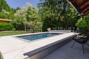a swimming pool in a patio with a table and a chair at Adventure Cottage with pool and big garden in Bled +17 photos