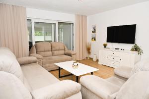 a living room with white furniture and a flat screen tv at Villa NOA in Jajce