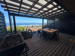a wooden deck with a table and chairs and the ocean at ALMAR House in Guaquen