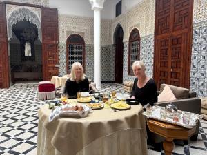 two women sitting at a table with food on it at Riad El abrar in Salé