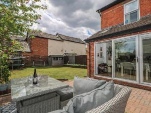 a patio with a couch and a table with a bottle of wine at Gordon Avenue in Camberley