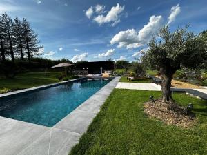 a swimming pool with a tree in the grass at Les Granges de Juvardeil in Juvardeil