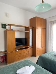 a bedroom with a tv and a large wooden cabinet at Pilgrimos Apartments in Ierissos