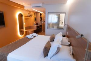 a bedroom with a large white bed and a bathroom at Hotel Sonata de Iracema in Fortaleza