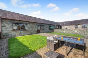 a garden with a table and chairs in front of a stone house at 3 Bed in Llanfairpwll oc-22999 in Llanfairpwllgwyngyll