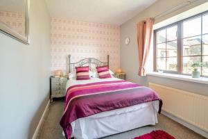 a bedroom with a bed with pink and purple sheets at 3 Bed in Llanfairpwll oc-22999 in Llanfairpwllgwyngyll