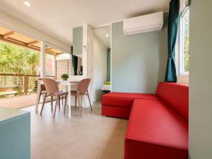 a living room with a red couch and a table at Camping Al Porto - Mini Glamping & Mobile Homes in Nago-Torbole