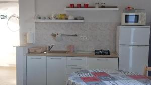 a kitchen with white cabinets and a white refrigerator at Apartman Biba in Lubenice +29 photos