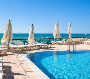 a pool with chairs and umbrellas next to the ocean at חדר נוף לים הרצליה in Herzliya B