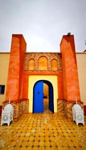 a building with a blue door and two chairs at Riad Azwaw in Er Rachidia