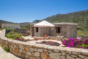 a stone wall with an umbrella and chairs and flowers at Lithos House in Avlóna