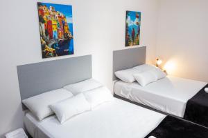 two beds in a room with white walls and paintings at Komfort House Premium in Medellín