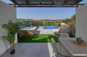 a patio with a tub and a table and chairs at Sagit luxury suites in Elqosh