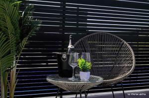 a wicker chair with a bottle of wine and a glass at Sagit luxury suites in Elqosh