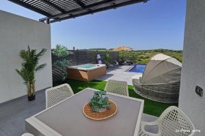 a patio with a table and chairs and a hot tub at Sagit luxury suites in Elqosh
