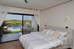 a bedroom with a white bed and a view of a pool at Sagit luxury suites in Elqosh